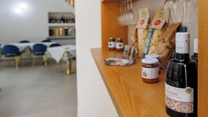 Interior de restaurante con un mostrador de madera que exhibe diferentes productos alimenticios y una botella de aceite de oliva.