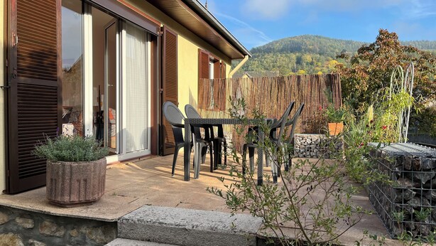 A patio with a table and chairs, a stone staircase, and a wooden fence. - Maisonnette "chez Georges" (Metzeral)