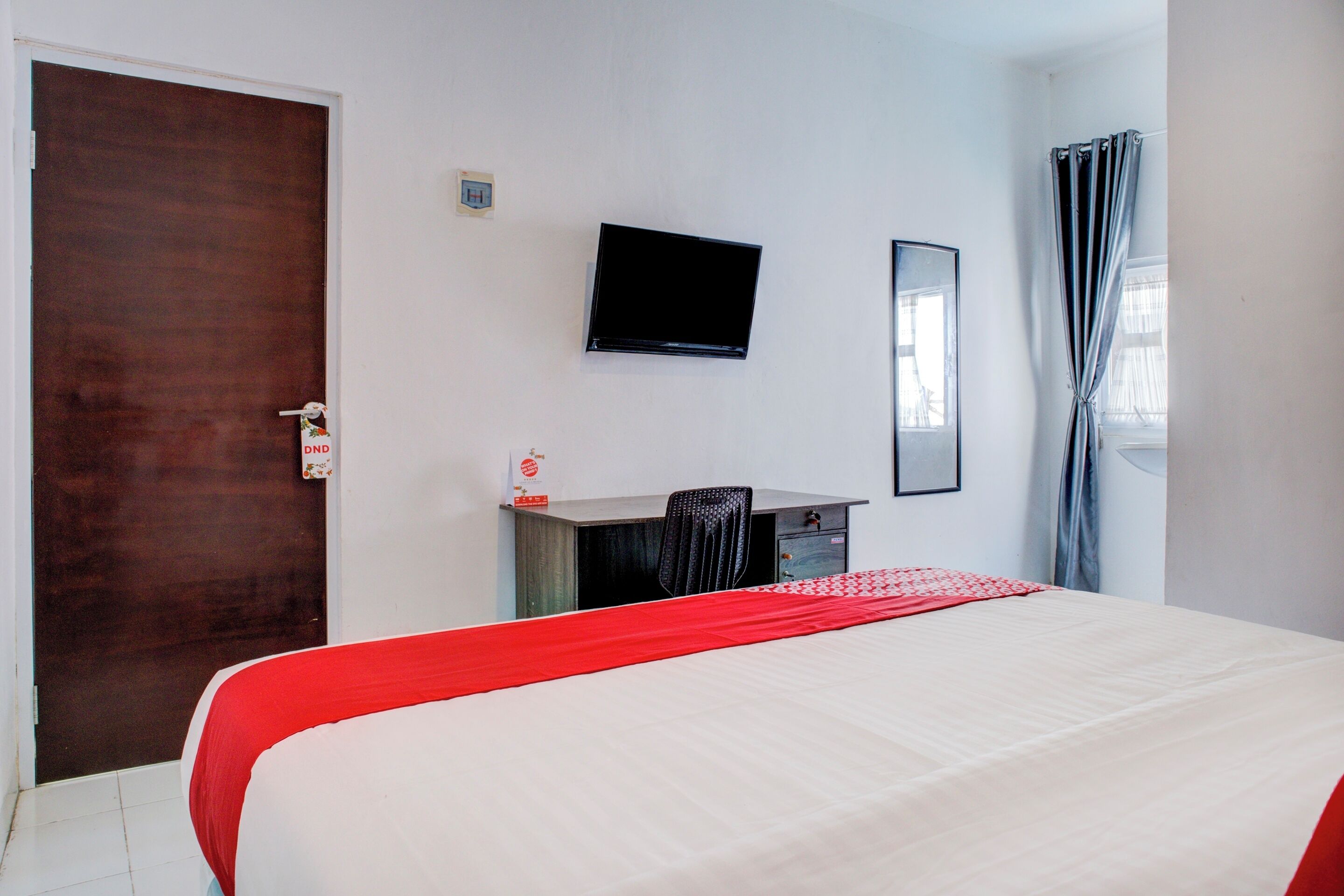 Une chambre d’hôtel avec un lit, un bureau, une télévision et une porte.