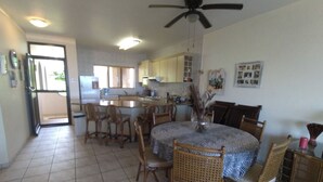 A spacious kitchen with a dining area, featuring a central island, wooden chairs, and a ceiling fan.