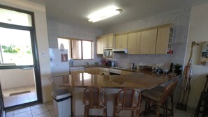 A kitchen with a central island, wooden chairs, a microwave, and cabinets.