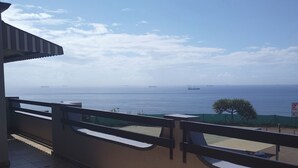 A balcony with a view of the sea and ships.