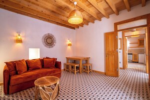 Una habitación acogedora con techo de madera, un sofá rojo, una mesita redonda y suelo estampado.