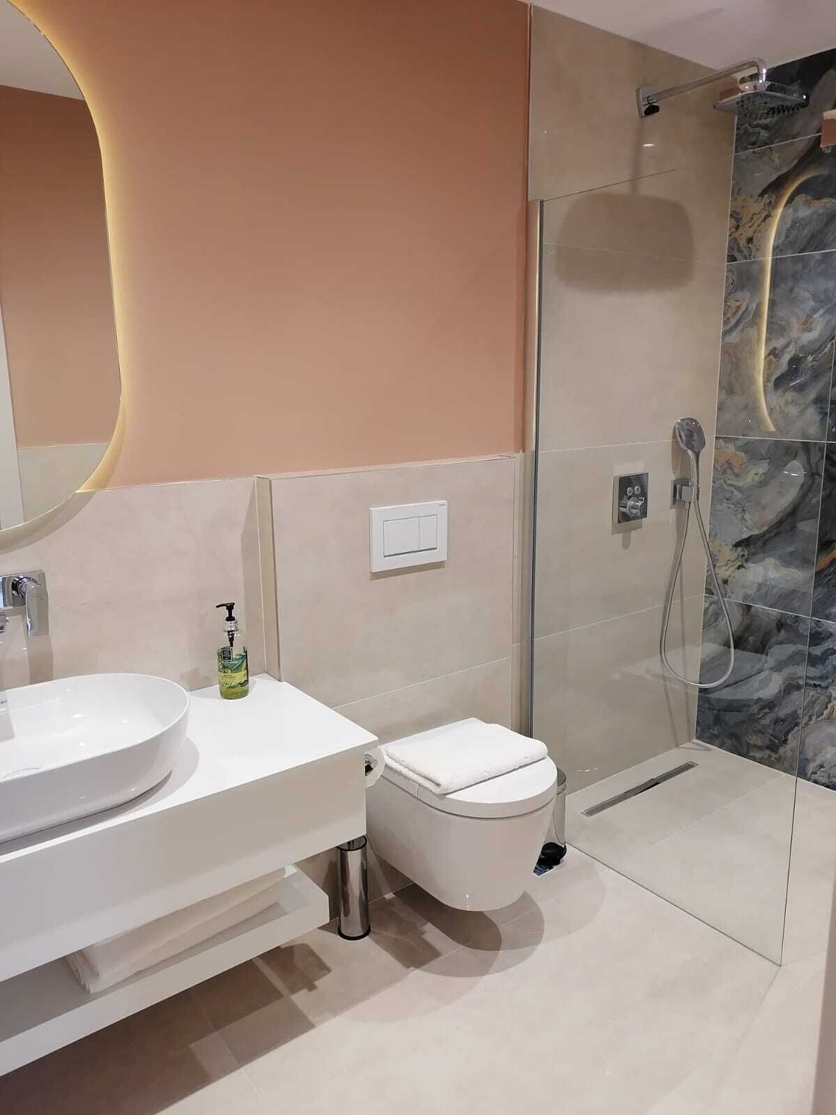 Ein modernes Badezimmer mit einem großen, weißen Waschbecken, einer Toilette und einer Duschkabine.