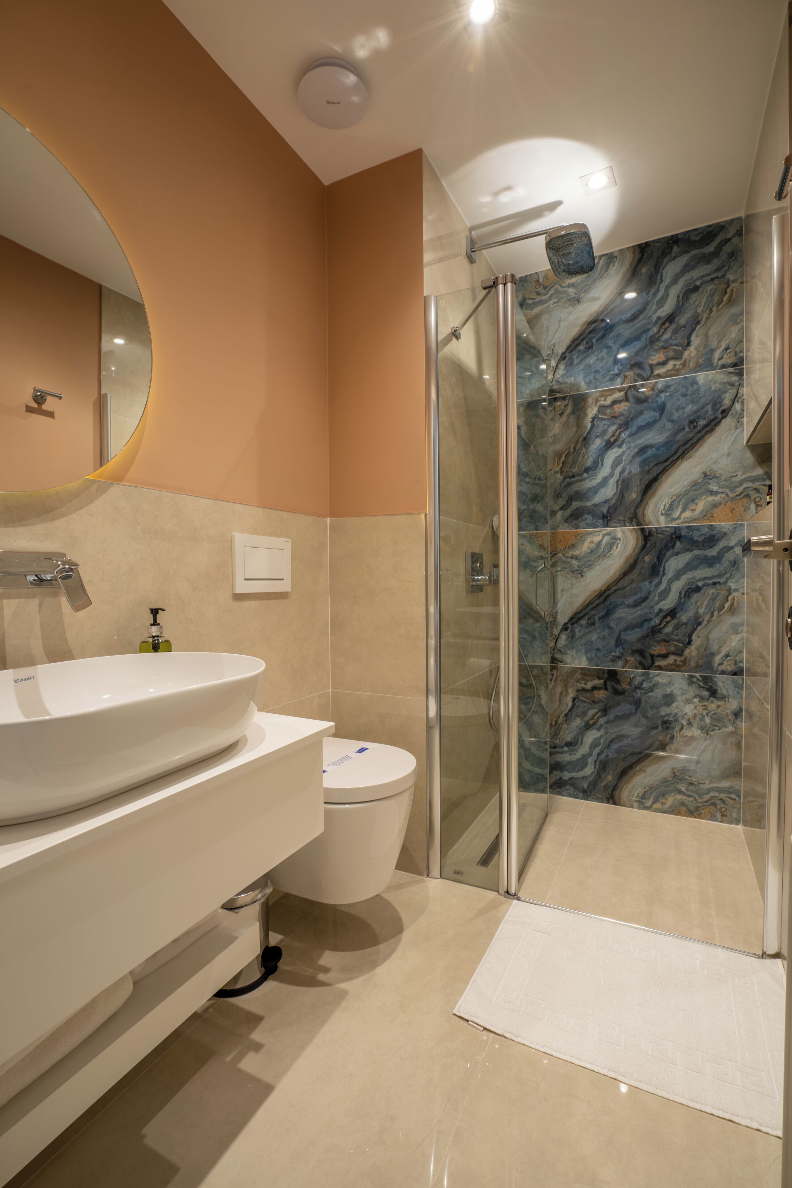 A modern bathroom with a large oval sink, a toilet, and a glass-enclosed shower.