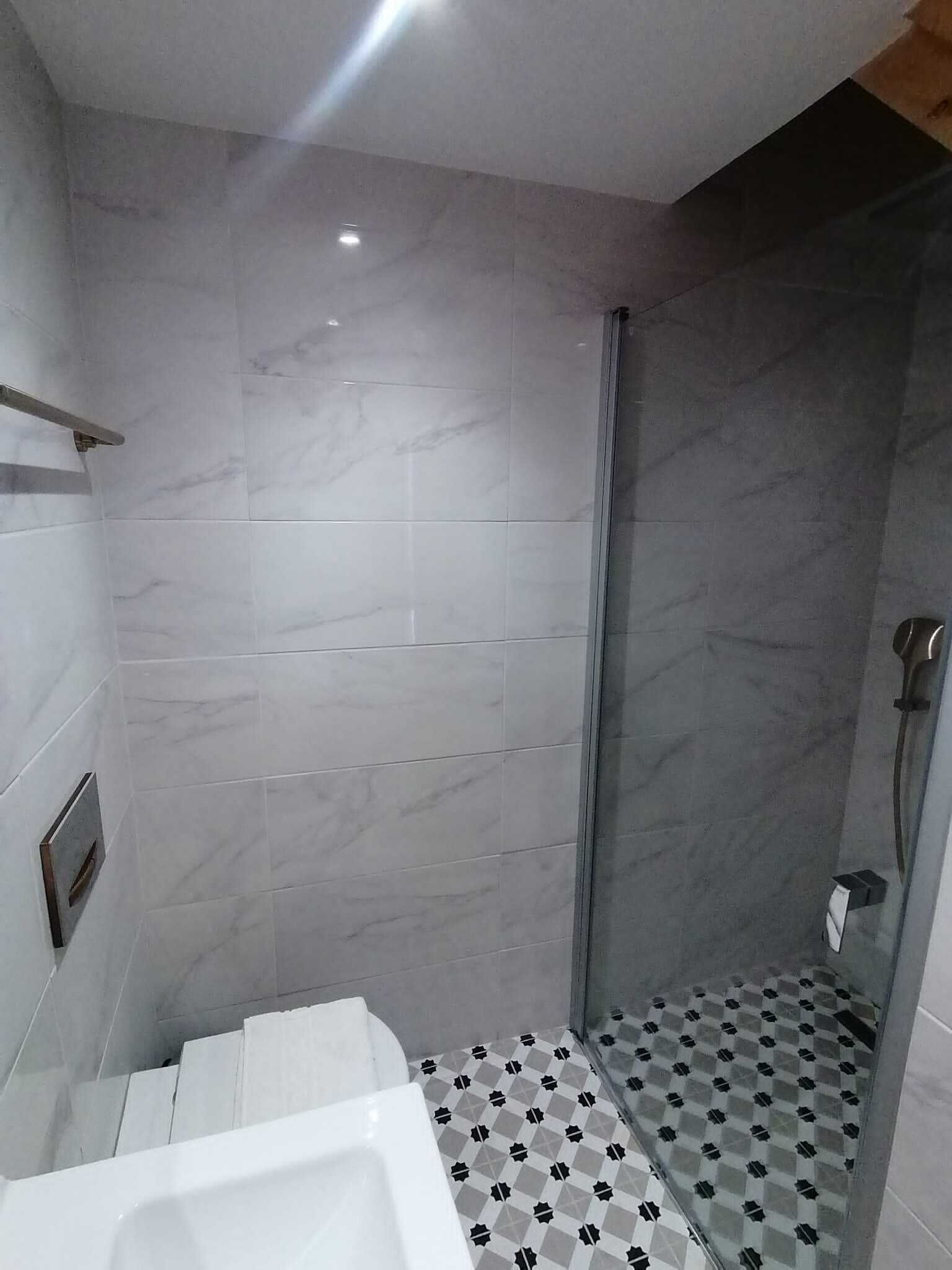 A modern bathroom with a shower, tiled walls, and a checkered floor.