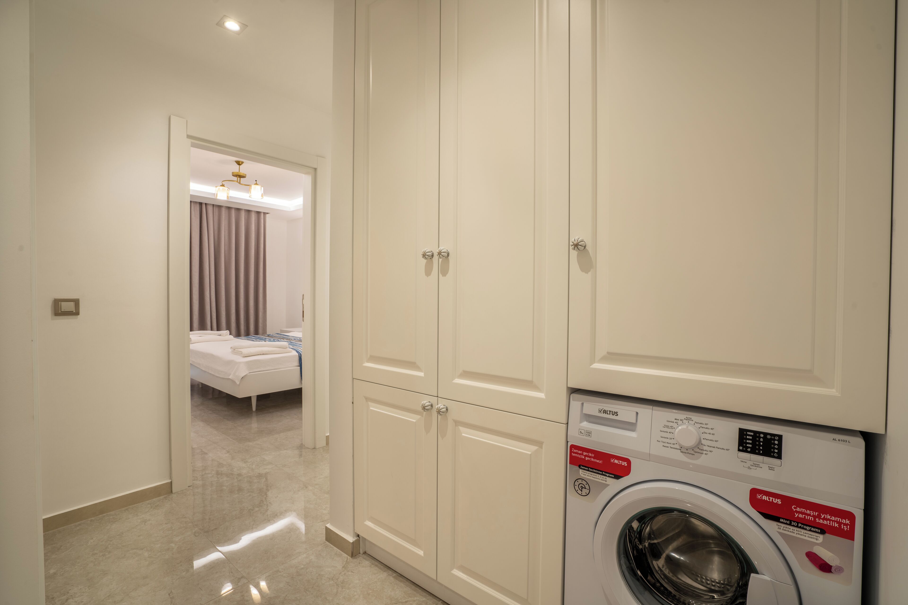 A hotel room with a bed, a washing machine, and a wardrobe.