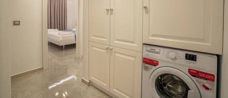 A hotel room with a bed, a washing machine, and a wardrobe.