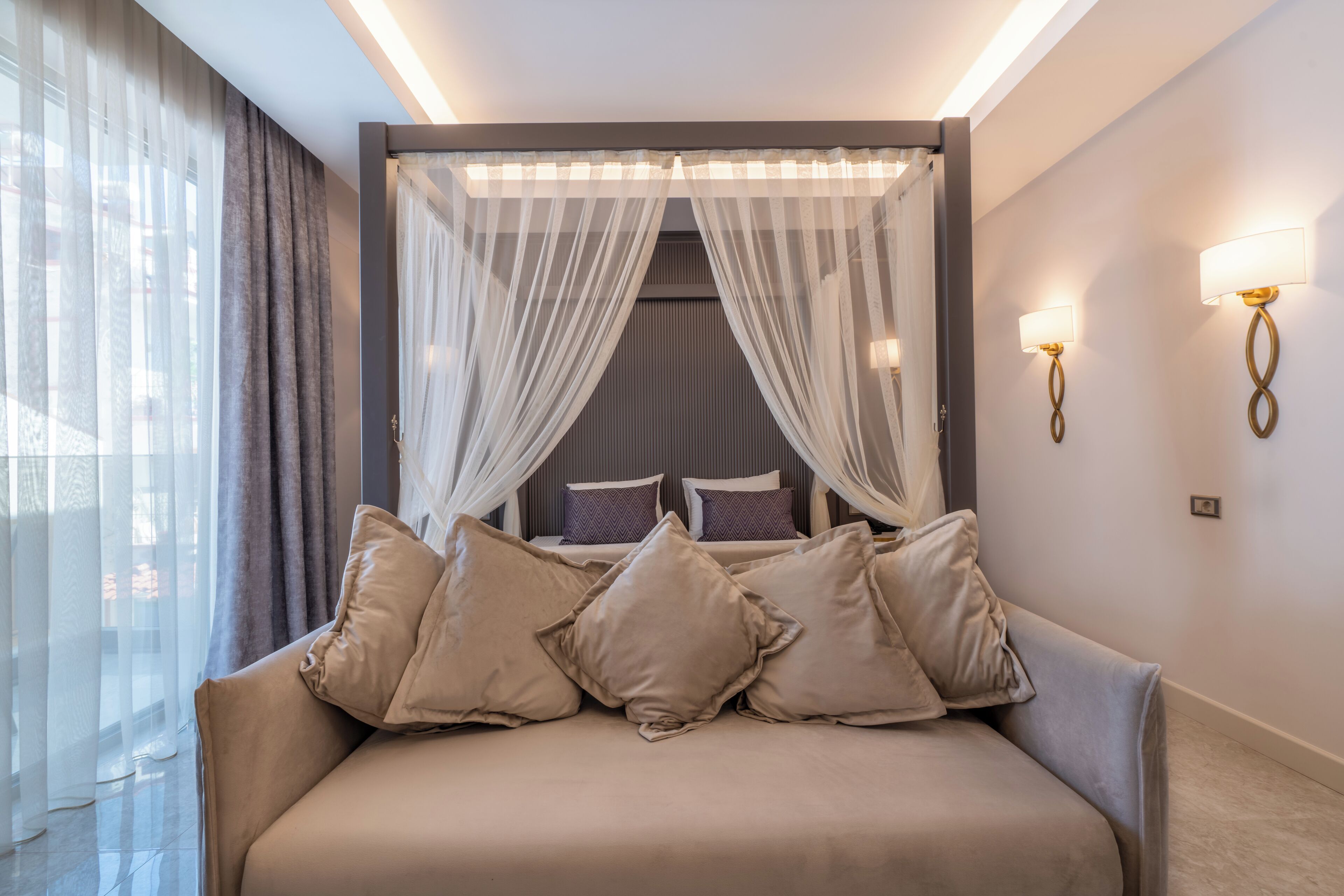 Quarto com cama, cortinas e luminárias na parede.