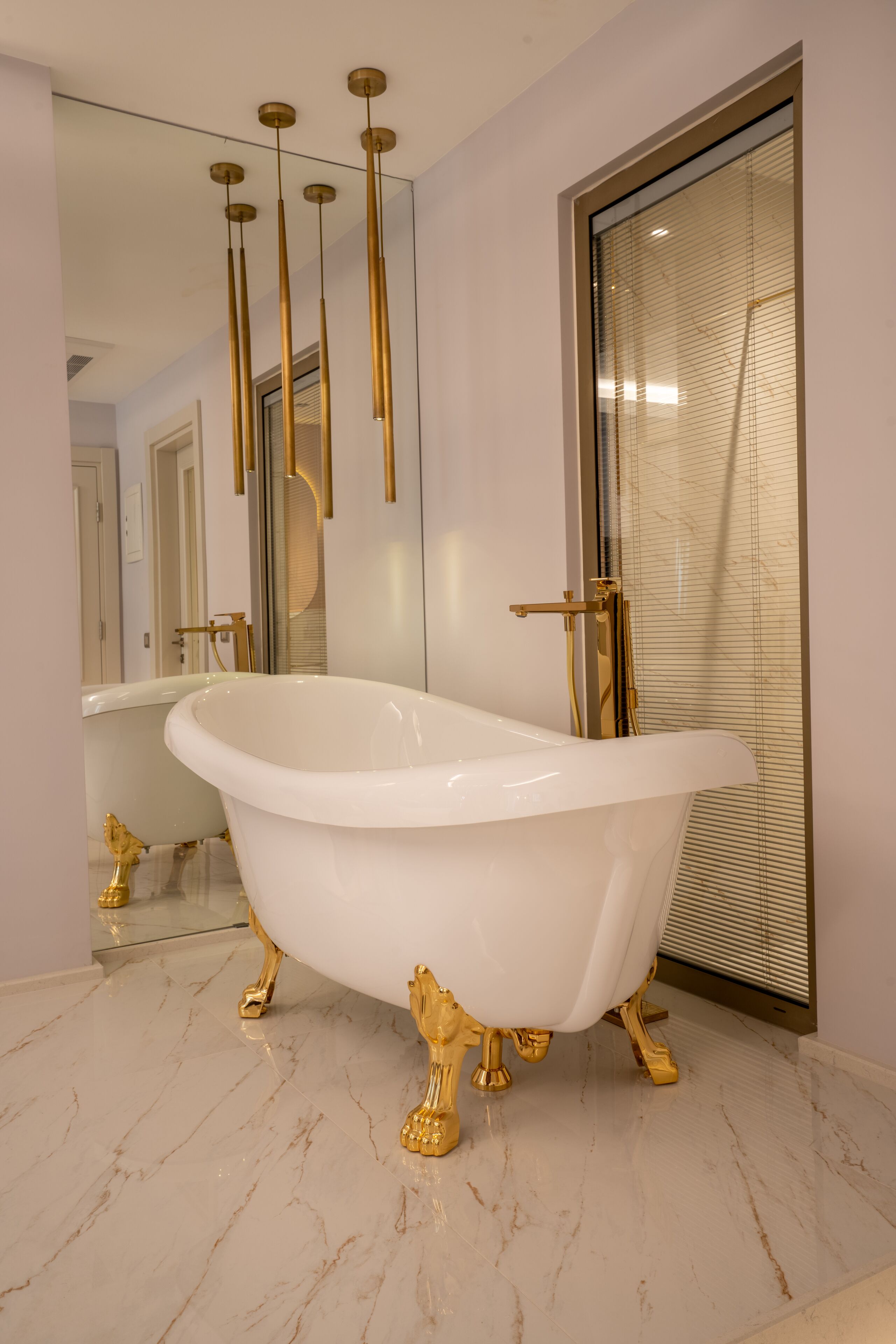 A luxurious bathroom with a freestanding bathtub, gold fixtures, and a large mirror.