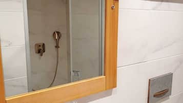 Ein Badezimmer mit einem spiegelnden Holzrahmen, einem weißen Waschbecken mit modernem Wasserhahn und einer Duschkabine aus Glas.