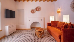 A cozy living room with a fireplace, a sofa, a TV, and patterned flooring. - Muhtar Hotel (Kas)