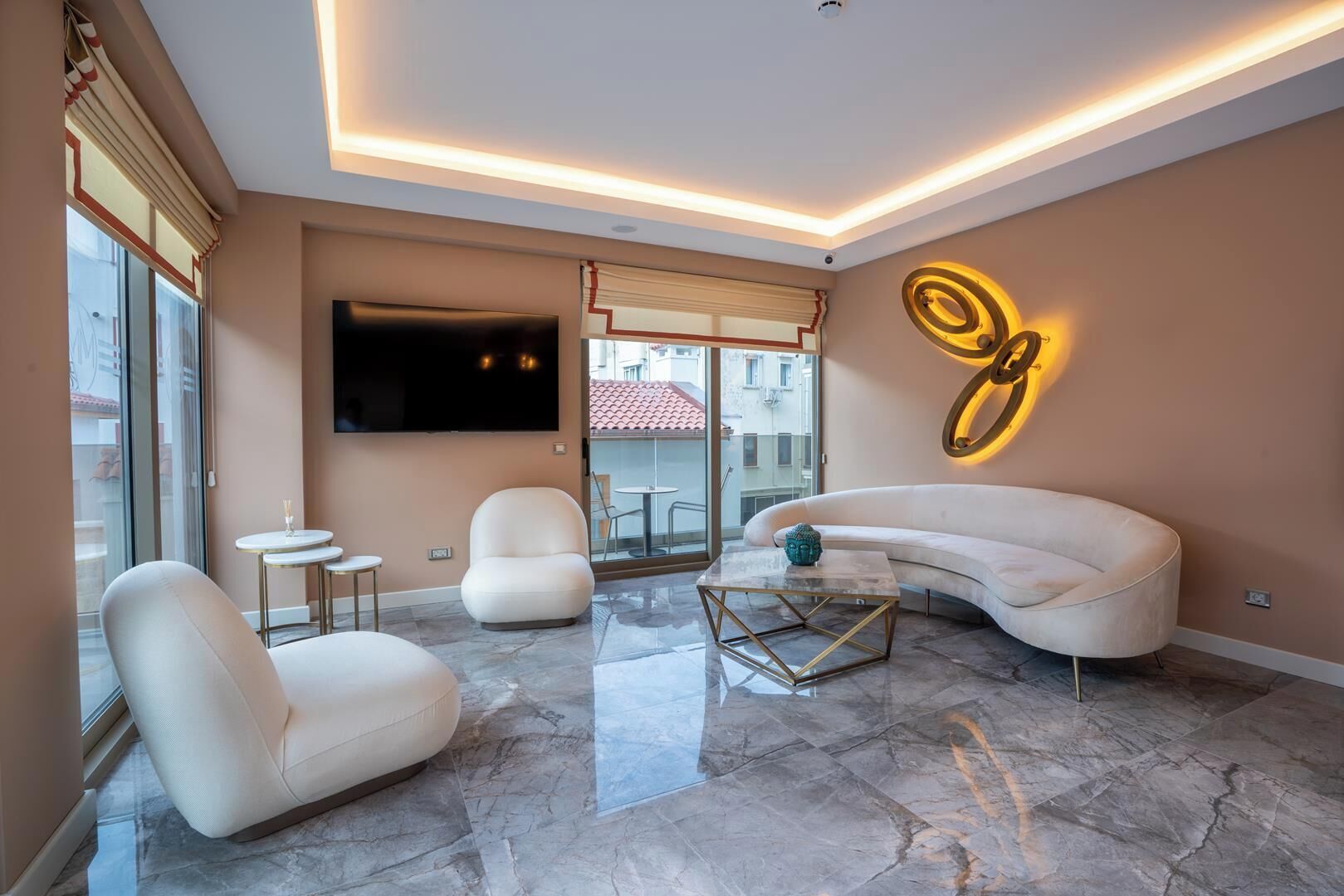 A modern living room with a curved sofa, two armchairs, a coffee table, and a TV mounted on the wall.