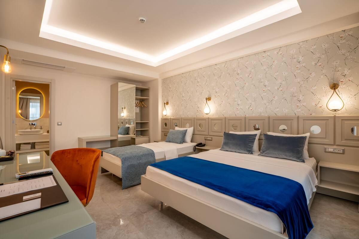 A modern bedroom with a large bed, two smaller beds, a desk, and a chair.