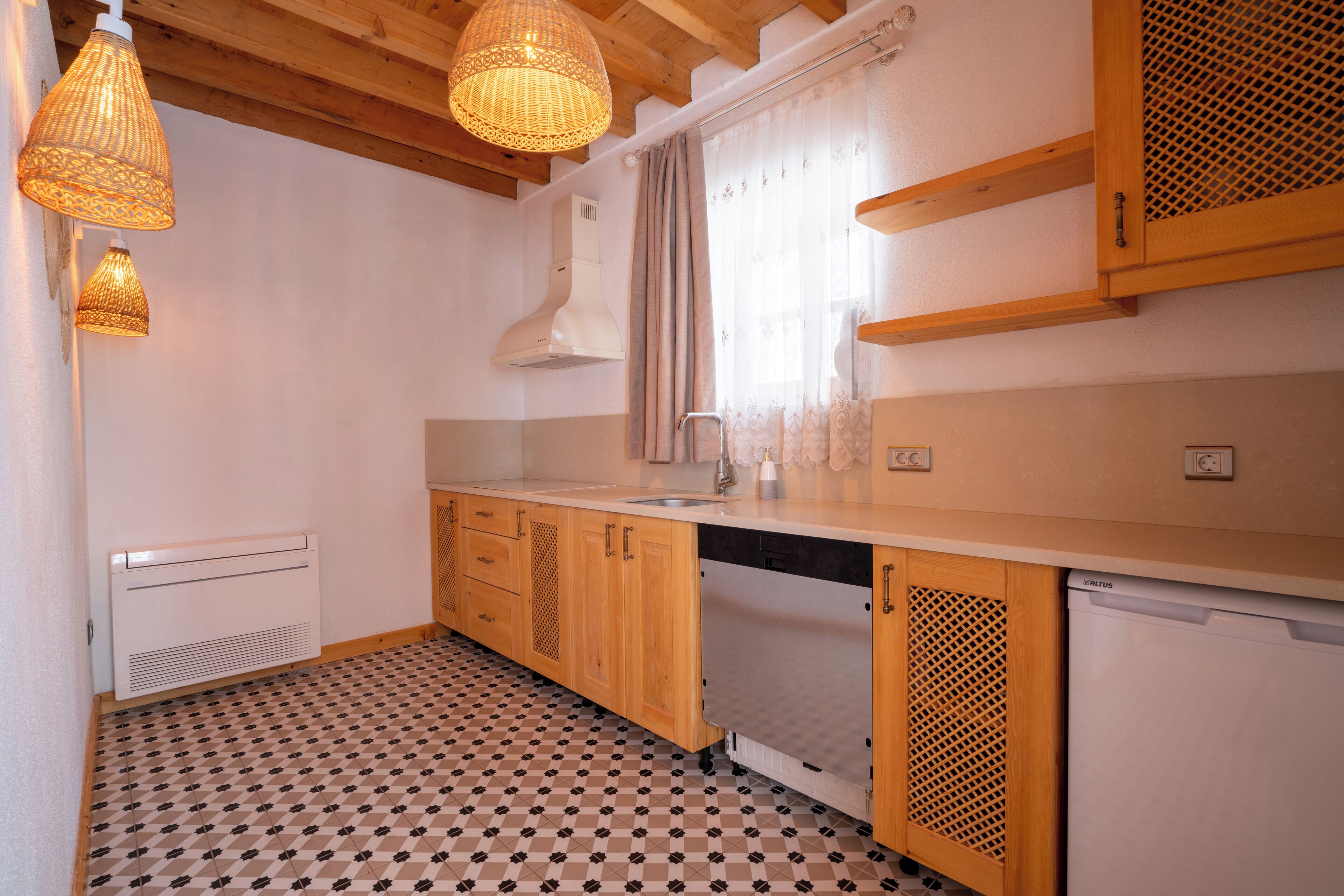 A kitchen with wooden cabinets, a white dishwasher, and a patterned floor.