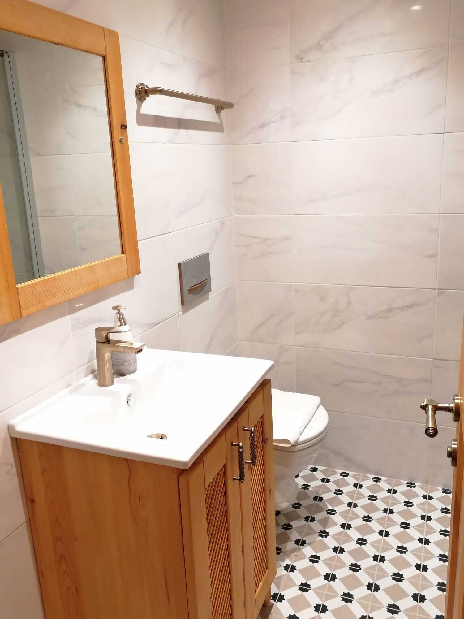 Een badkamer met een houten wastafel, een spiegel, een handdoekhouder en een toilet.