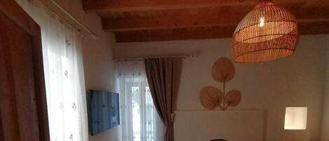A cozy room with a wooden ceiling, a patterned floor, a sofa, a table, a hanging light fixture, and a fireplace.