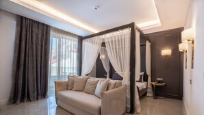 A modern bedroom with a four-poster bed, a sofa, and a bedside table. - Muhtar Hotel (Kas)