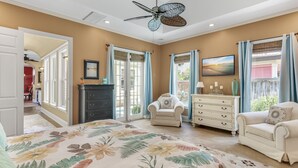 A bedroom with a bed, two chairs, a dresser, and a ceiling fan. - Home with Pool in the Gated Community of Caribe (Destin)
