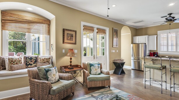 A spacious living room with wicker furniture, a dining area with a bar, and large windows with blinds. - Home with Pool in the Gated Community of Caribe (Destin)