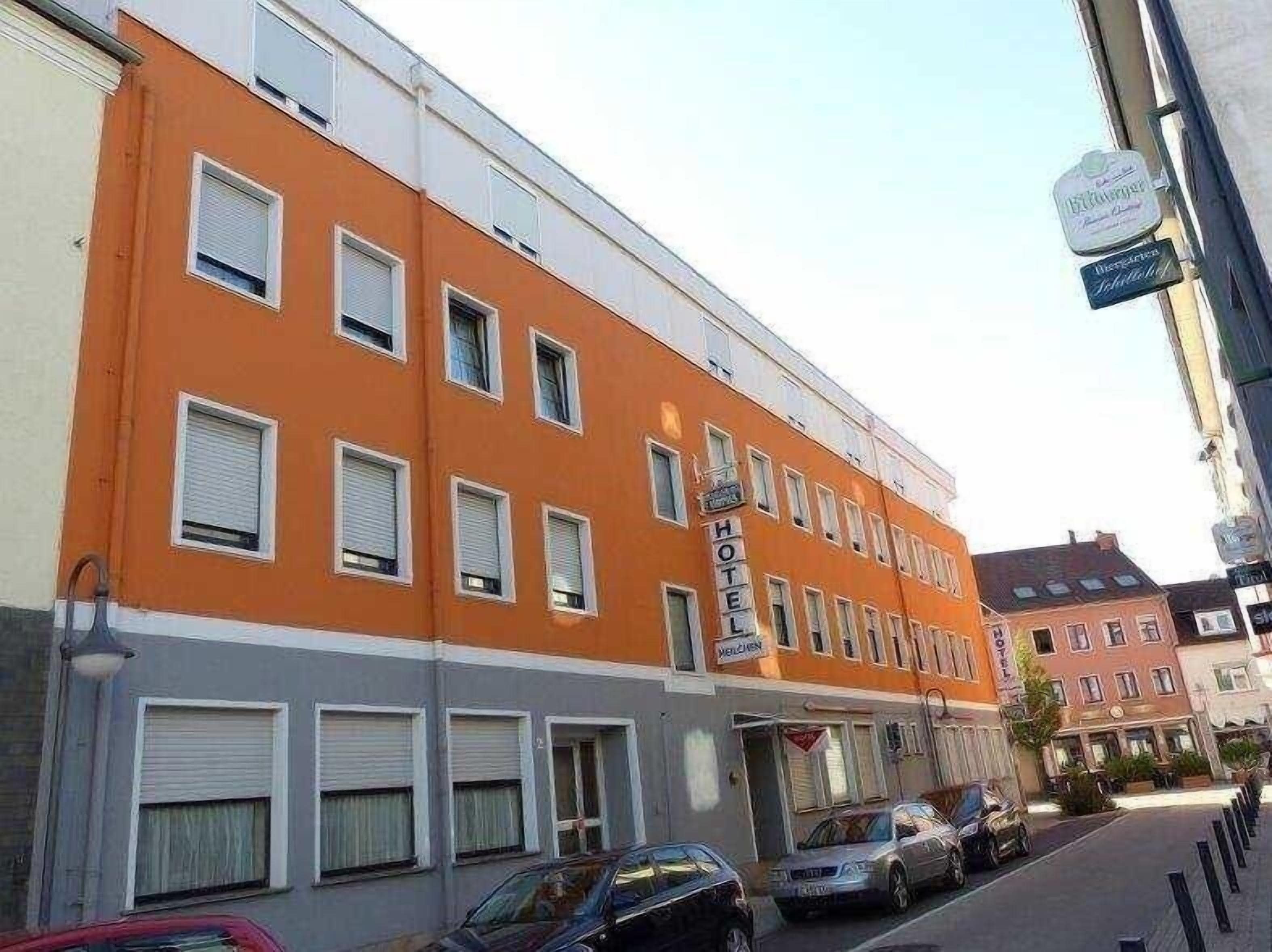 Et hotel med en lys orange facade, mange vinduer, og et skilt der angiver, at det er et hotel.