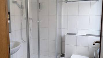 Ein modernes Badezimmer mit einer Duschkabine, einem weißen Waschbecken und einer Toilette.