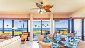 A spacious dining area with a glass table, leather chairs, and a view of the ocean.