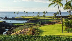 A golf course with a view of the ocean and palm trees.