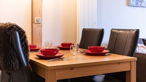 Una mesa de comedor con cuencos rojos y copas de vino, rodeada de sillas de cuero.