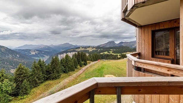Una cabaña de madera con un balcón que da a un paisaje montañoso.