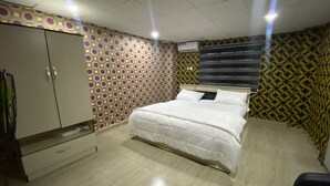 A bedroom with a bed, wardrobe, and patterned walls. - Chukzie Suites & Apartments (Lagos)