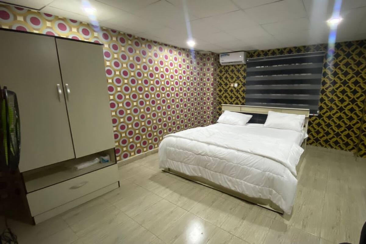 A bedroom with a bed, wardrobe, and patterned walls.