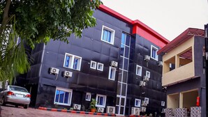 A multi-story building with a black facade and red roof. There are multiple windows and air conditioning units attached to the exterior walls. - Chukzie Suites & Apartments (Lagos)