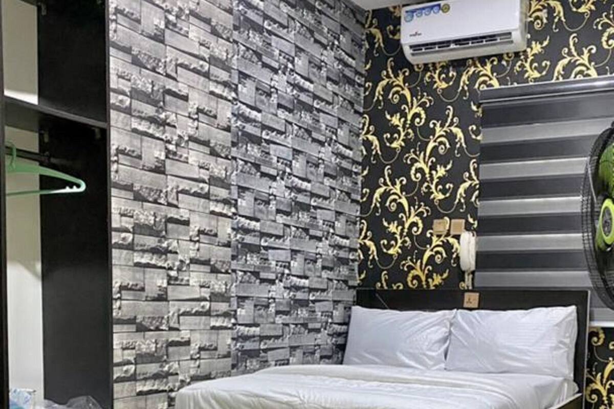 A modern bedroom with a bed, a wardrobe, and an air conditioning unit.