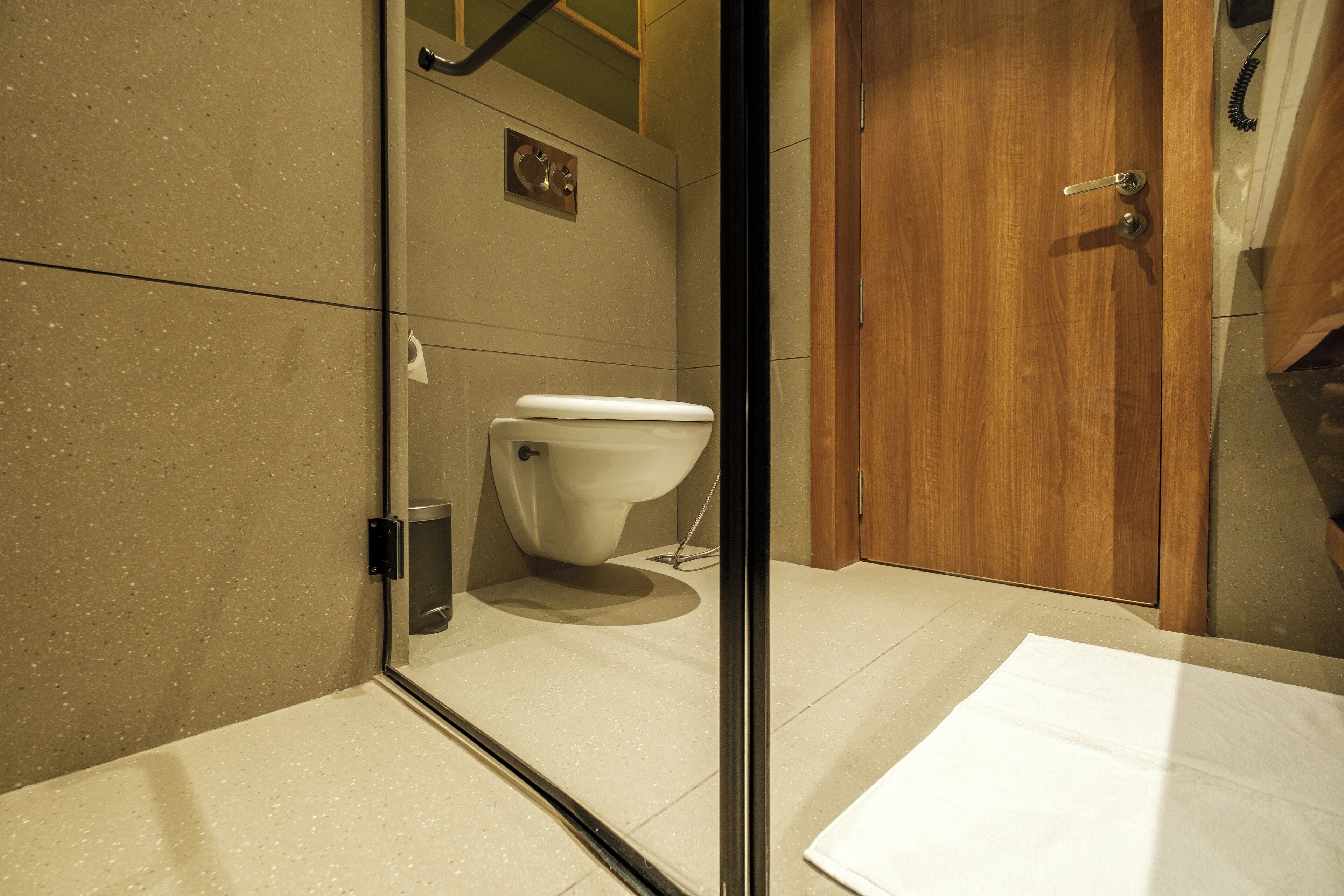 Un baño moderno con inodoro, zona de ducha y puerta de madera.