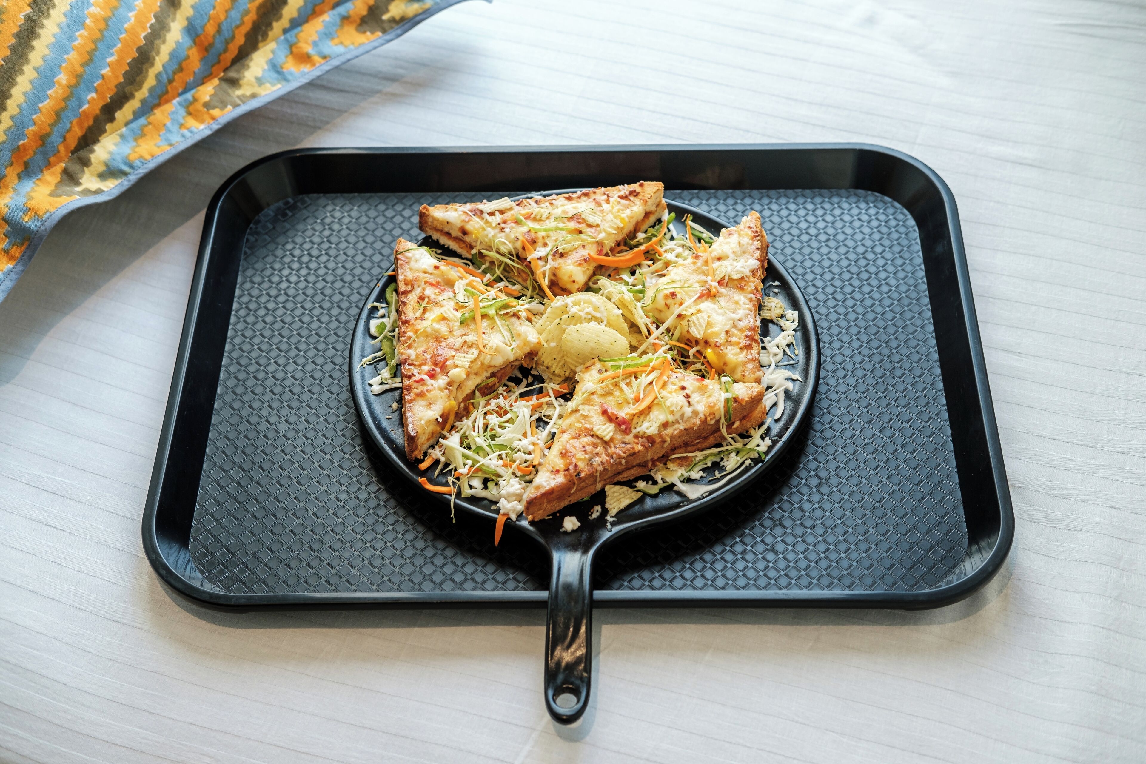 A black non-stick frying pan with a textured surface on a light-colored wooden table.