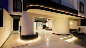 Un moderno vestíbulo de hotel con un diseño espacioso, que cuenta con grandes columnas, una zona de recepción e ingreso bien iluminado.