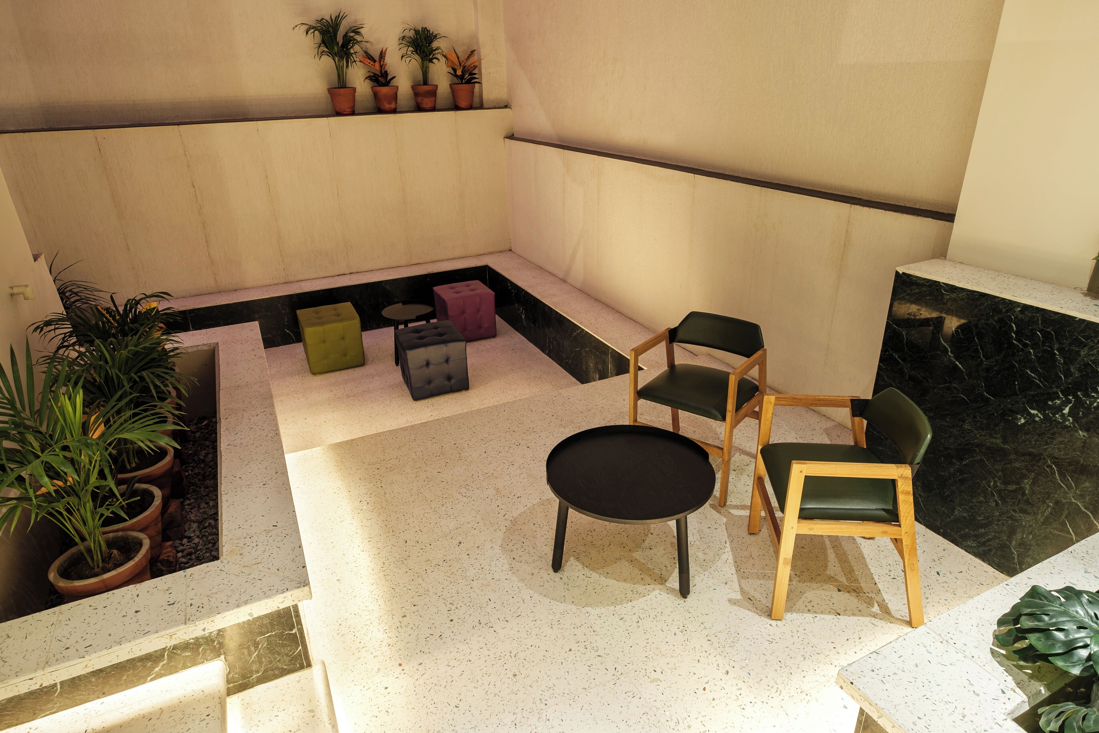 A modern interior with a seating area featuring a round table and two chairs, a small sofa, and a potted plant.