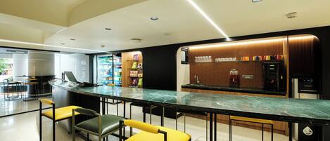 A modern bar area with a marble countertop, bar stools, and a beverage dispenser.