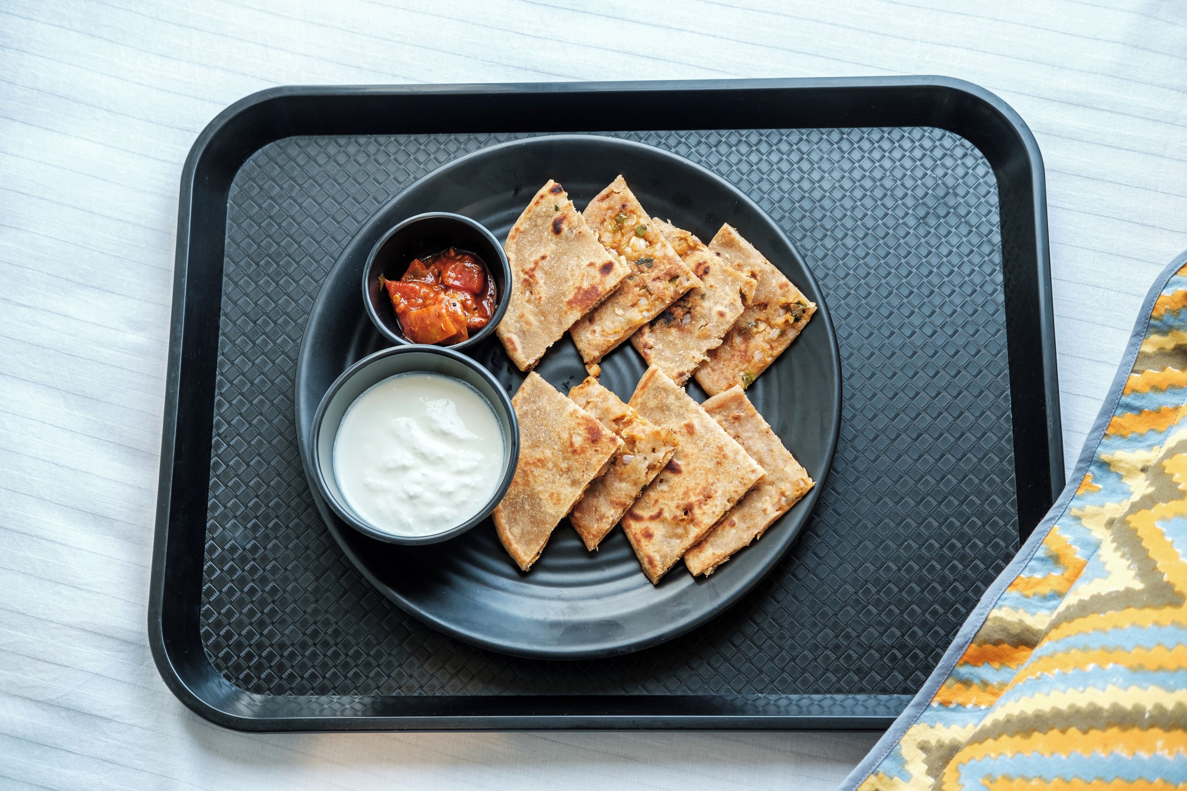 A tray with flatbreads and two dipping sauces on a textured mat.