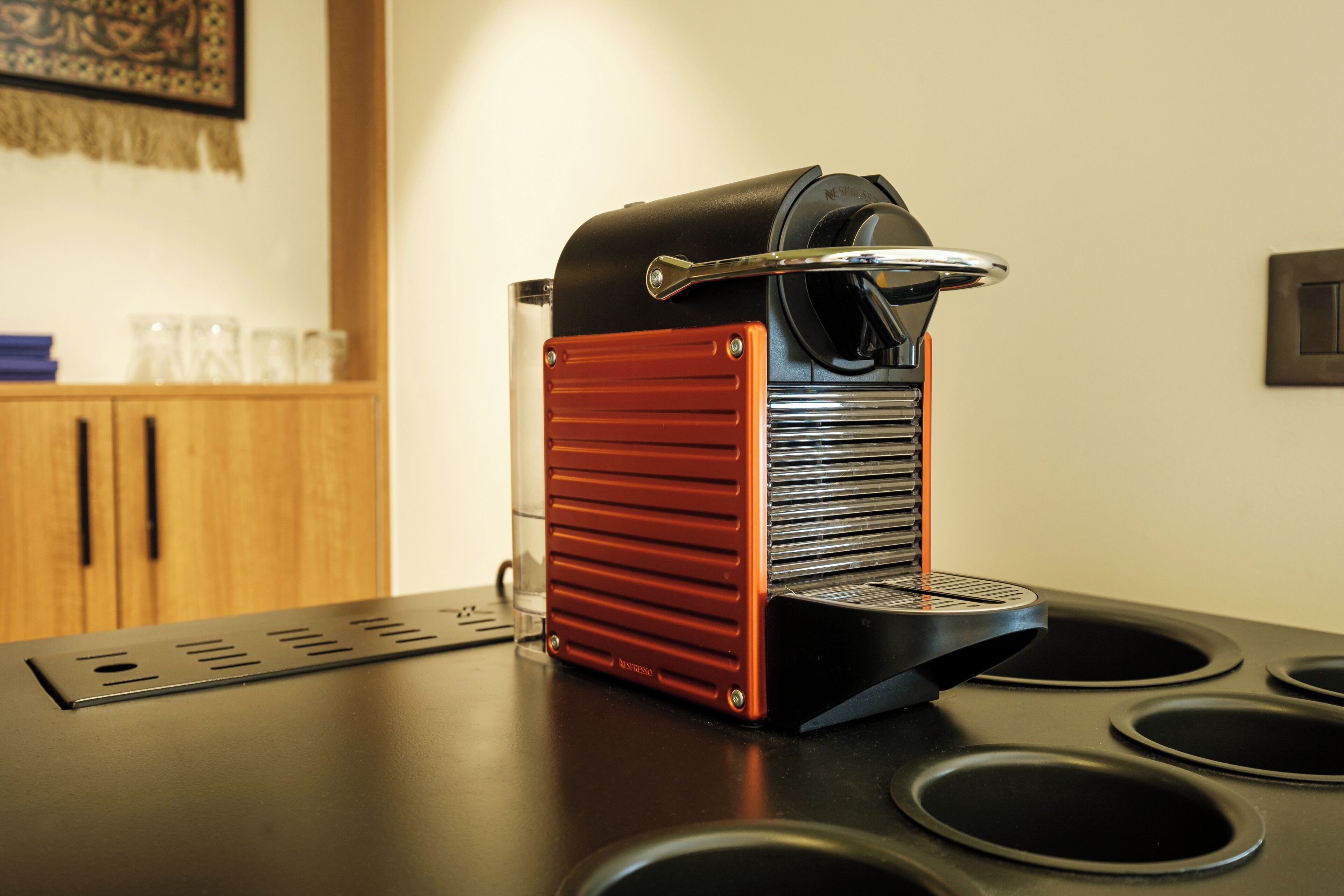 A coffee machine on a kitchen counter with a wooden cabinet in the background.