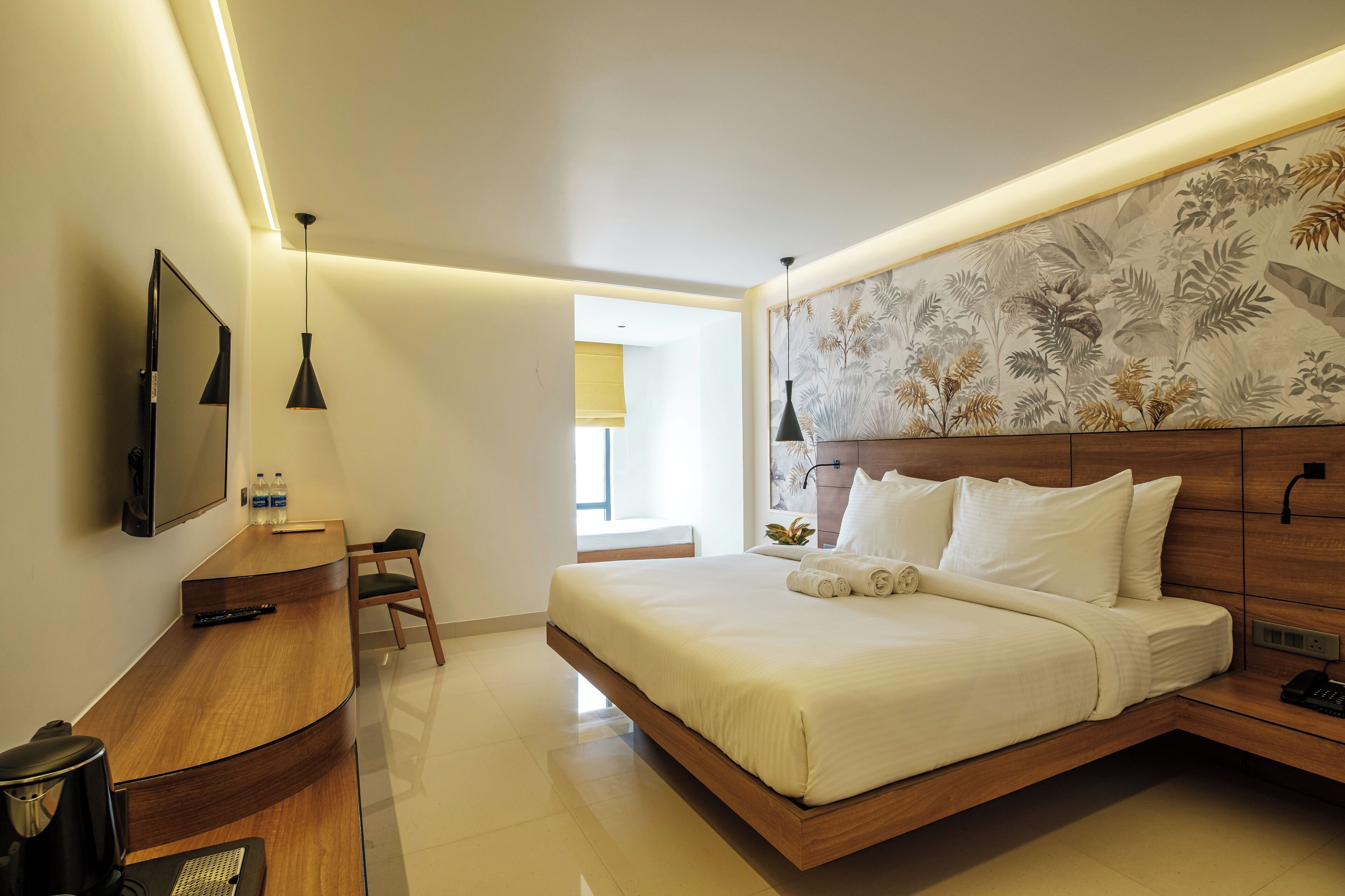 A modern hotel room with a bed, a desk, and a television.