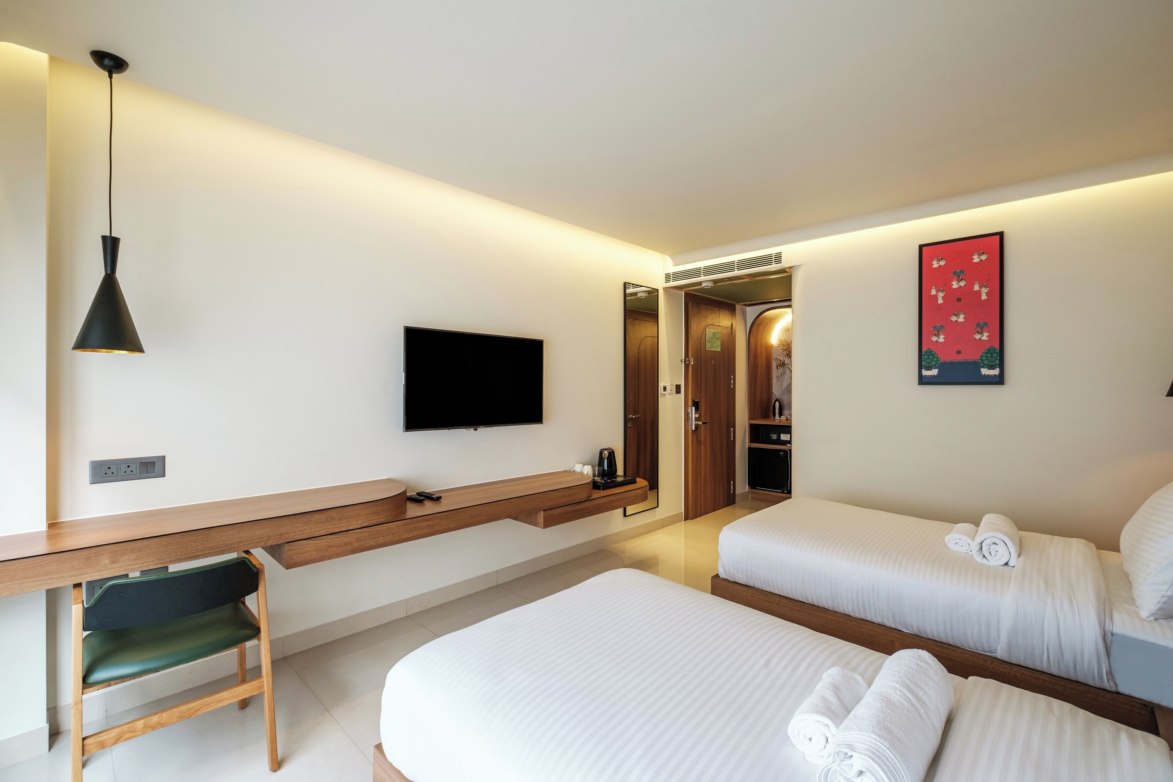 A hotel room with a bed, a desk, a chair, a TV, and a bathroom door.