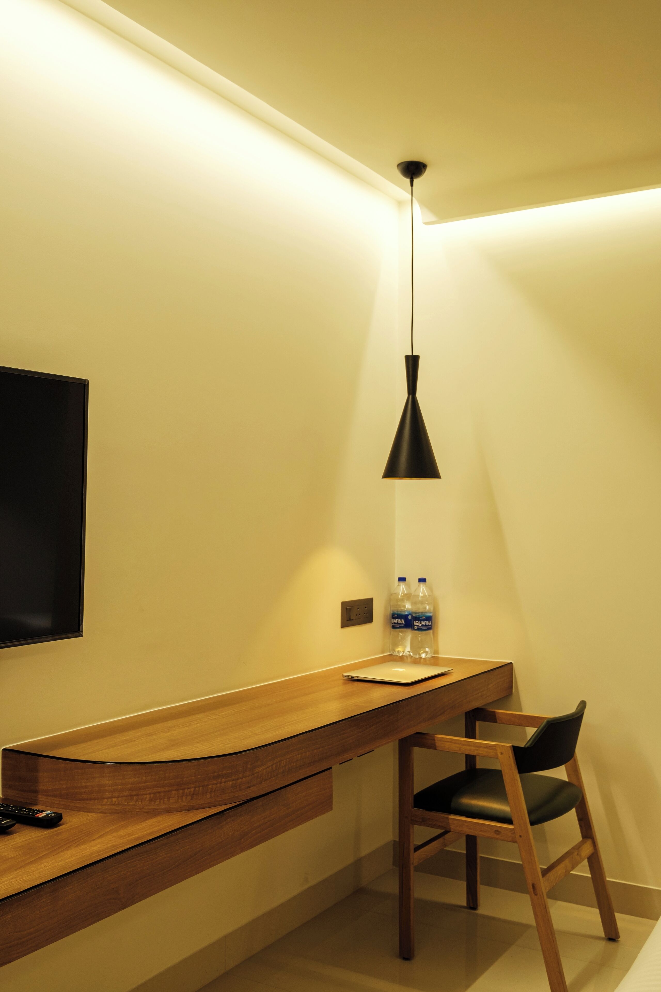 A modern bathroom with a wooden vanity, a black pendant light, and a chair.