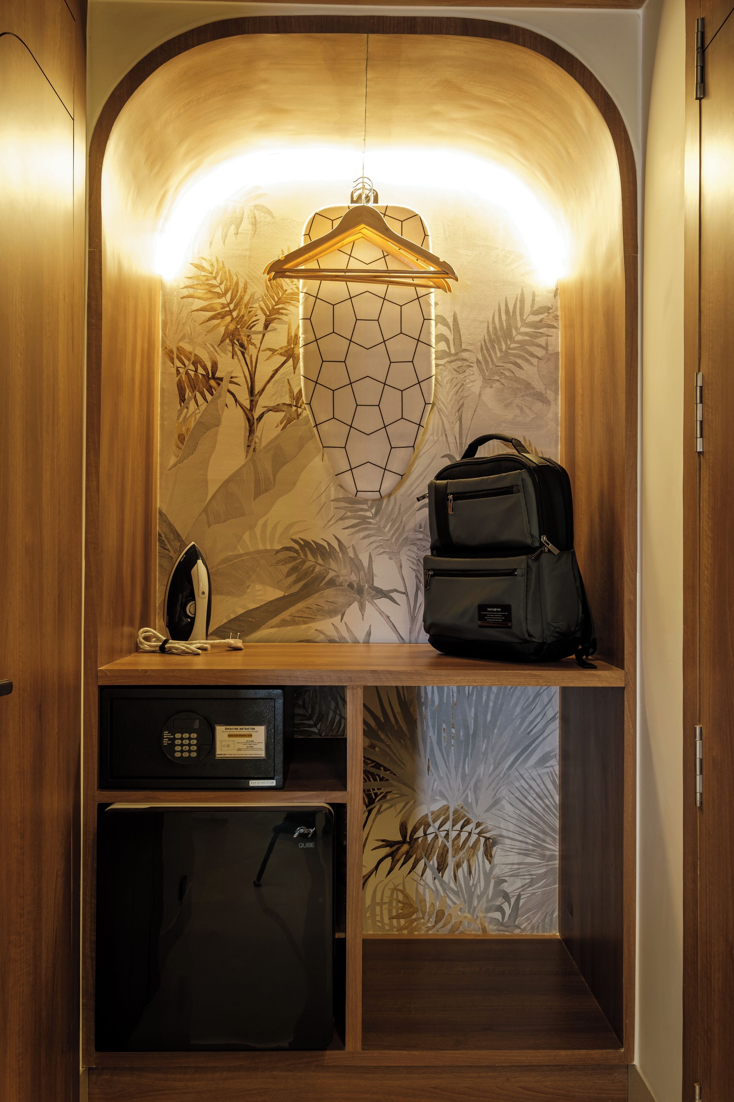 A compact storage area with a microwave, a small refrigerator, and a hanging garment rack.