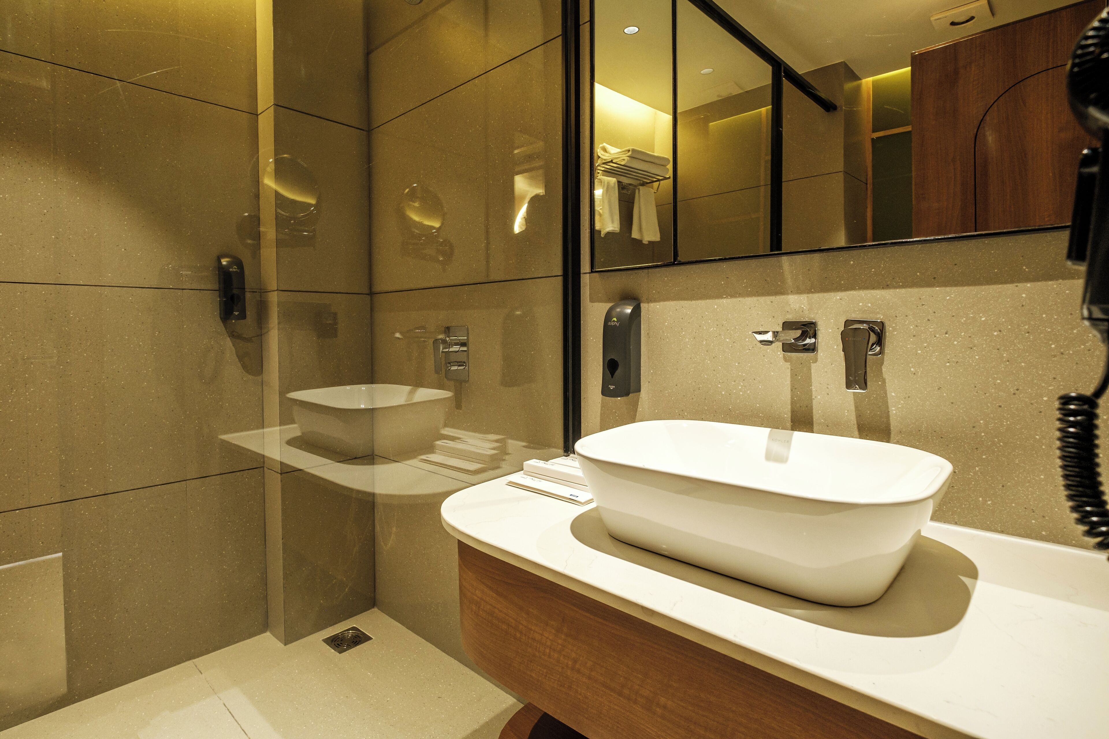 A modern bathroom with a large mirror, a sink with a basin, and a shower area.