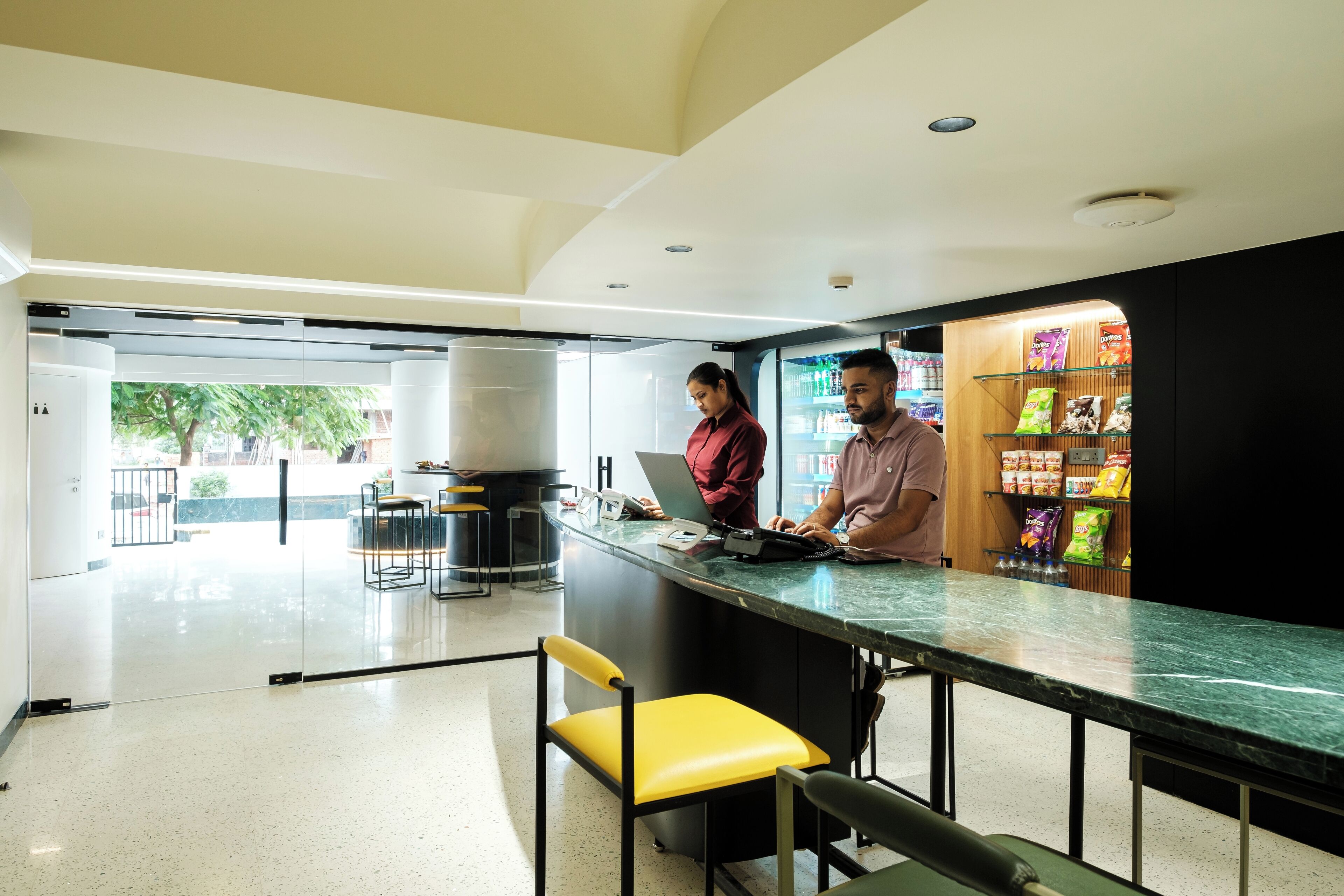 A modern interior with a reception desk, a laptop, and a man and woman working.