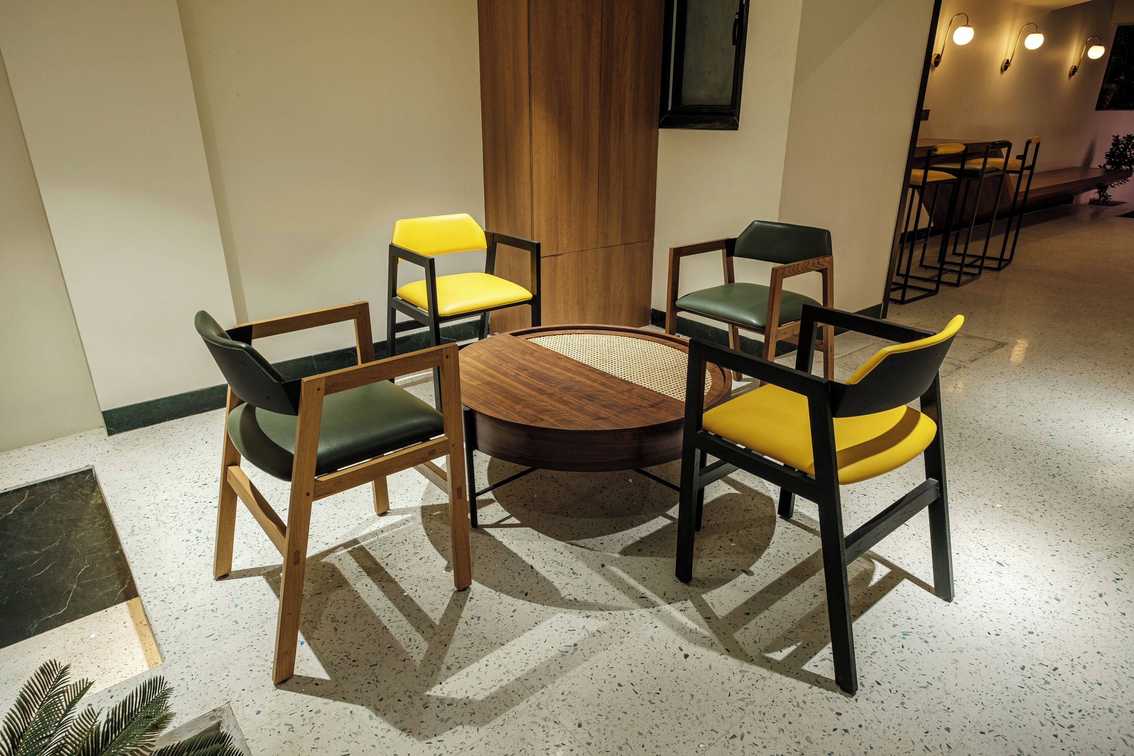 A conference room with a round table and six chairs, some with yellow cushions.