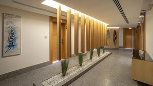 A modern hallway with wooden panels, a reception desk, and a surfboard mural. - Ewaa Express Hotel-Al Shati (Jeddah)