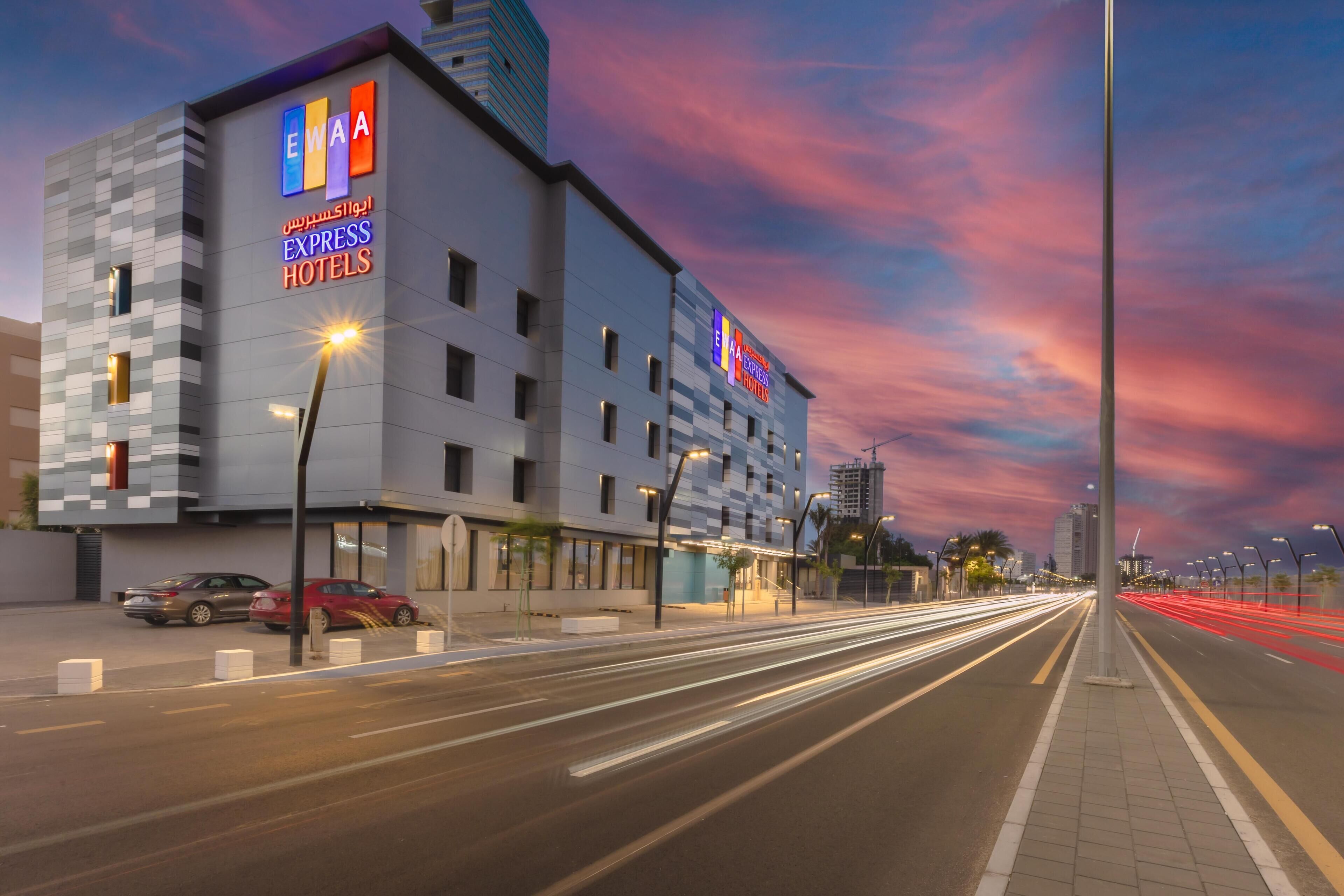 A modern hotel building with a prominent sign for EWA Express Hotels.